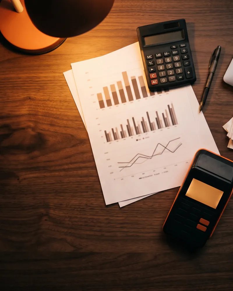 Relatórios de vendas, calculadora e maquininha sobre a mesa